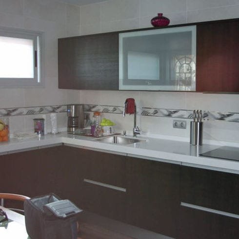 Cocina con mobiliario marrón y encimera clara en Móstoles